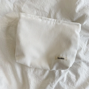Detailed close-up of white corduroy fabric texture and woven Sozakka tag on a makeup bag