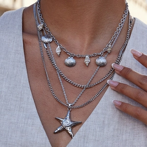 Silver tiered necklace featuring detailed starfish and seashell pendants on a model