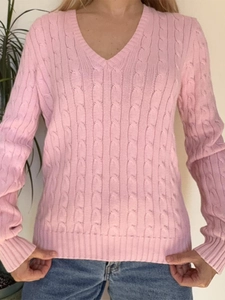 Détail du pull en maille rose à col en V montrant la texture torsadée et les bords-côtes