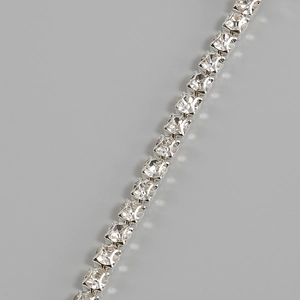 Détail des zircons cubiques carrés sur un collier de style tennis en métal argenté