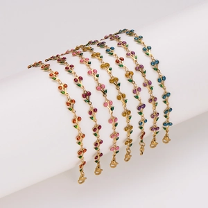 Close-up of golden cherry bracelets with colorful crystal rhinestones and green enamel