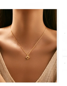 Detail view of a vintage gold hollow diamond pendant with a ruby red stone on a model