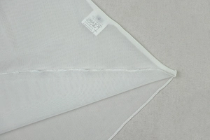 Detail of white hollow dress showing fine seam edges and 100% nylon washing label