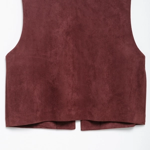 Close-up of bohemian burgundy suede vest hem with detailed ethnic embroidery texture