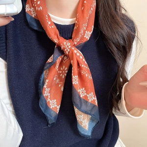 Close-up of printed silk scarf necklace with vibrant orange and navy blue patterns