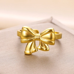Macro shot of polished gold bow ring with adjustable open band and fine metal texture