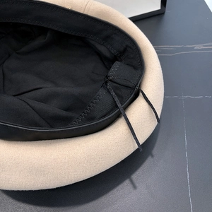 Dettaglio del berretto in lana beige con fodera nera e cordino di regolazione interno