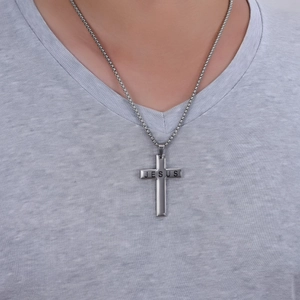 Détail du pendentif croix argentée avec gravure JESUS sur un mannequin masculin