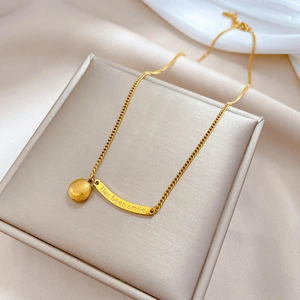 Detail of gold titanium necklace with smiley face and Has Been Smile engraved bar charm