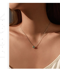 Close-up of S925 silver necklace with sparkling green round gemstone pendant on model