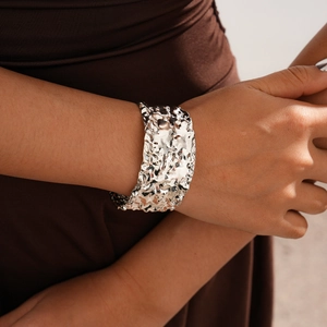 Detail view of a wide silver lava texture cuff bracelet with irregular metallic patterns