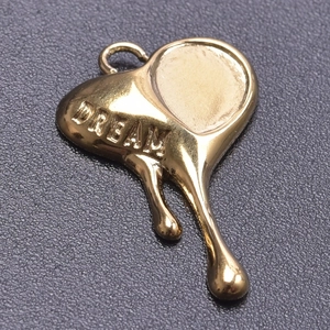 Macro shot of gold heart pendant with melting effect and DREAM engraving detail