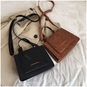 Gros plan sur des sacs carrés rétro chic en similicuir noir et marron avec logo doré