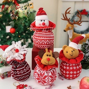 Detailed view of four knitted Christmas gift bags with Santa, deer, and snowman designs