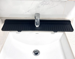 Detail of black silicone faucet mat with wave pattern drainage texture for kitchen sink