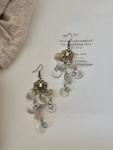 Detail of vintage hollow flower earrings with shell tassels and bronze alloy finish
