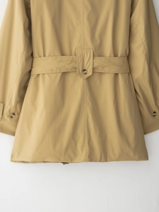 Détail de la ceinture et des boutons sur un trench-coat kaki à revers classique