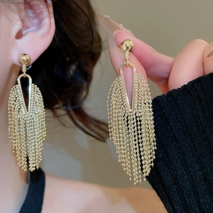Close-up of elegant gold tassel drop earrings featuring geometric triangular studs