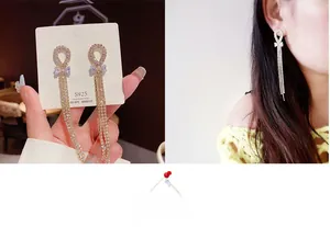 Detail of silver S925 bow earrings with long sparkling rhinestone tassels on model