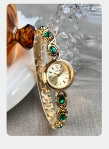 Gros plan sur la montre bracelet dorée à quartz avec pierres vertes et cadran Gedi