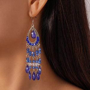 Macro detail of bohemian blue crystal fringe earrings with water-drop tassels and silver finish