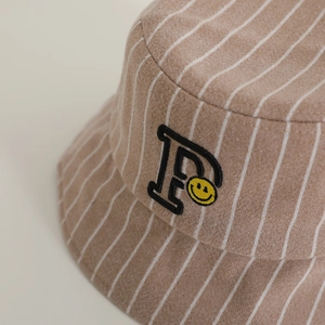 Close-up of light brown wool bucket hat with white stripes, letter P and smile embroidery