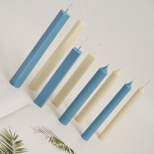 Detailed view of ribbed and smooth pillar candles in light blue and beige with cotton wicks