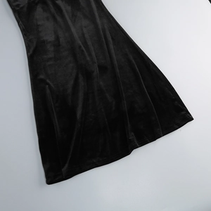 Detail of elegant black velvet dress showing smooth texture and draped slit hemline