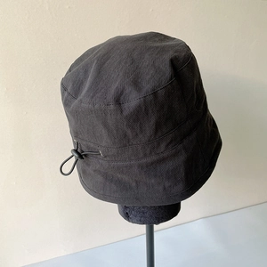 Detail of adjustable drawstring buckle on a breathable black summer bucket hat