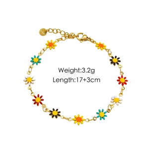 Detailed view of colorful daisy enamel charms and S.Steel logo on a gold chain bracelet