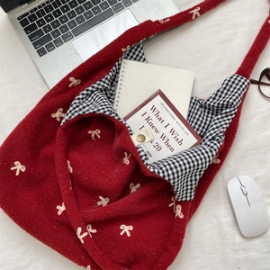 Close-up of red wool tote bag showing embroidery bow detail and gingham lining