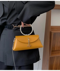 Detail of yellow leather handbag featuring a luxury rhinestone circular handle and chain