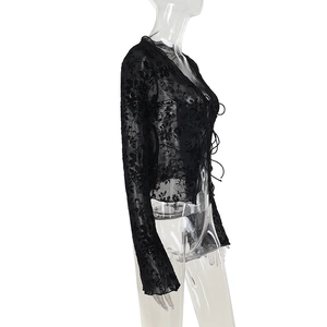 Detail of black lace blouse featuring floral sheer mesh fabric and front tie-up design