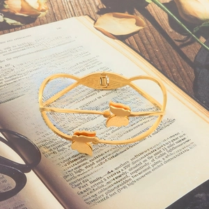 Detail of a golden butterfly stainless steel cuff bracelet on a vintage book background