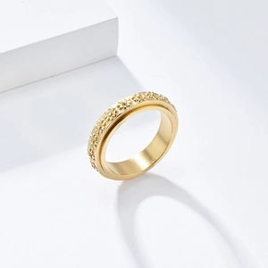 Macro detail of rotating gold stainless steel ring featuring relief daisy floral patterns