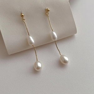 Macro shot of long golden tassel earrings with lustrous white freshwater pearls