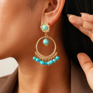 Close-up of bohemian hollow round earrings with turquoise beads and gold finish