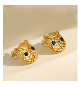 Detail of owl stud earrings with hammered gold texture and black gemstone eyes