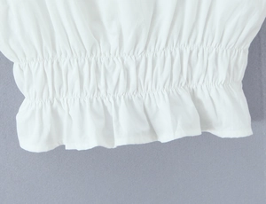 Close-up of white lace top with elastic smocking and ruffle hem detail