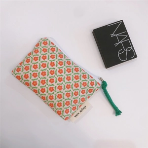 Detailed view of floral cotton pouch with green cord zipper and simple wish label