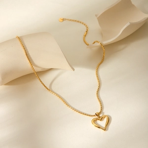 Close-up of golden hollow heart pendant on a thin metal chain with polished finish