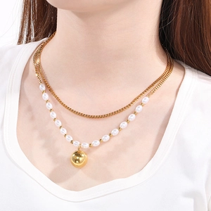 Detail shot of a double-layer necklace with gold ball pendant and white pearls on neck