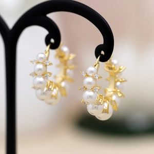 Elegant gold pearl hoop earrings with sparkling zircons on a classic jewelry stand