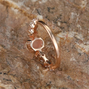 Macro detail of rose gold vintage oval ring with pink gemstone on natural rock background