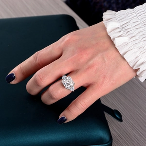 Macro shot of a sparkling three-stone S925 sterling silver ring on green silk