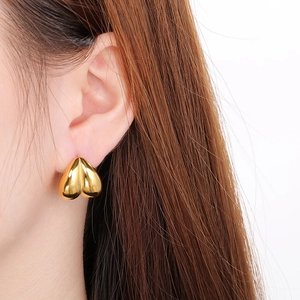 Close-up of a model wearing a polished gold heart-shaped stainless steel earring
