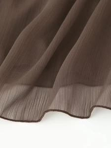 Macro shot of dark brown textured chiffon fabric showing delicate hem and airy weave