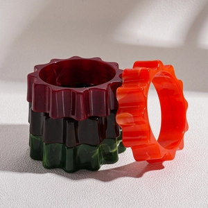 Exaggerated geometric wavy acrylic bangles set in deep burgundy green and orange