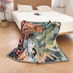 Artistic tiger and jungle pattern woven bohemian blanket with tassels on a bed
