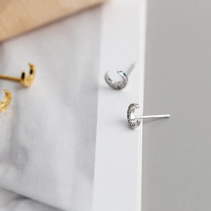 Close-up of crescent moon earrings with 925 silver hallmark and cubic zirconia stones